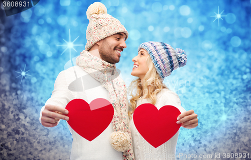 Image of smiling couple in winter clothes with red hearts