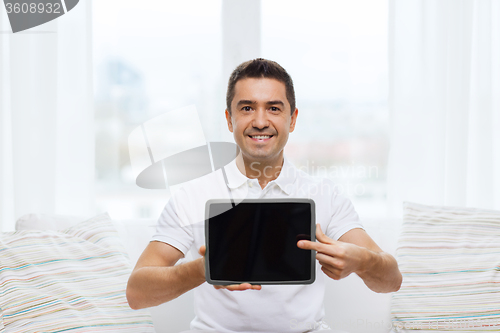 Image of smiling man showing tablet pc blank screen at home