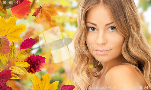 Image of beautiful young woman face over autumn leaves