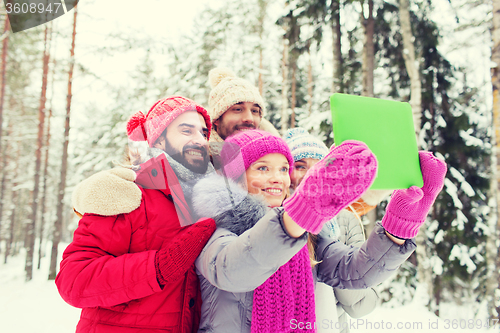 Image of smiling friends with tablet pc in winter forest