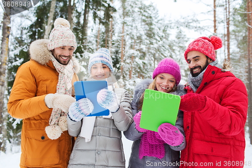 Image of smiling friends with tablet pc in winter forest