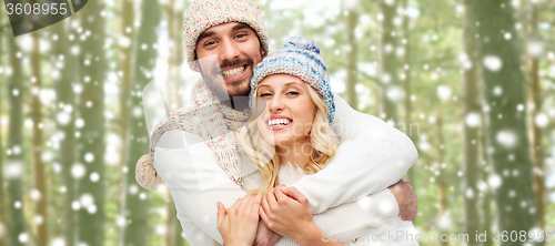 Image of happy couple in winter clothes hugging over forest