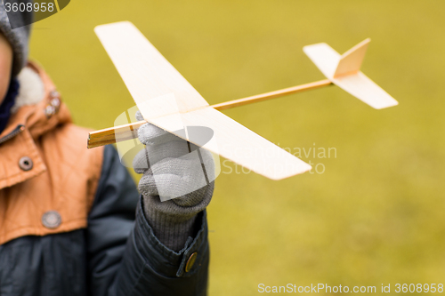 Image of close up of little boy holding toy plane outdoors