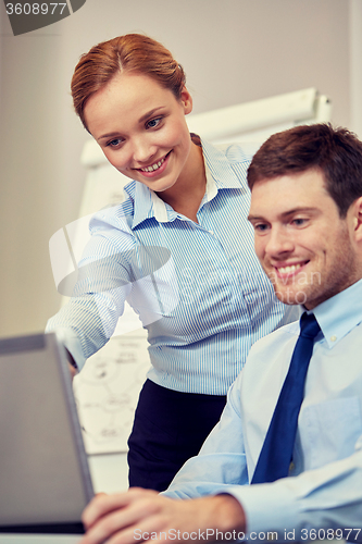 Image of smiling businesspeople with laptop in office