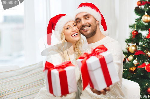 Image of happy couple at home with christmas gift boxes