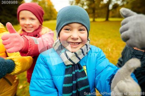 Image of happy children showing thumbs up in autumn park