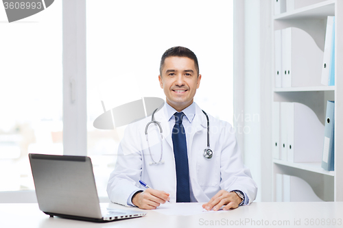 Image of smiling male doctor with laptop in medical office