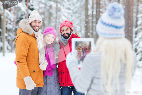 Image of smiling friends with tablet pc in winter forest