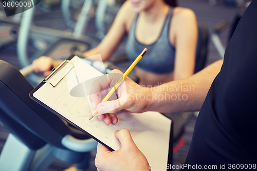 Image of close up of trainer hands with clipboard in gym