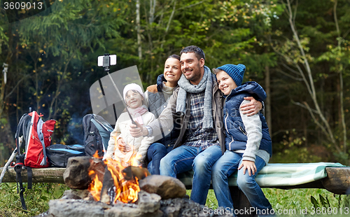 Image of family with smartphone taking selfie near campfire