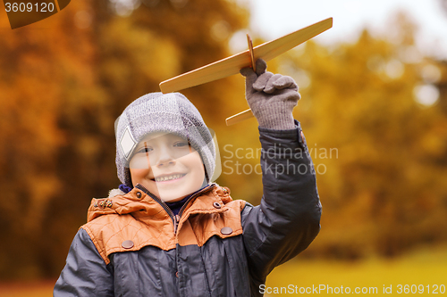 Image of happy little boy playing with toy plane outdoors