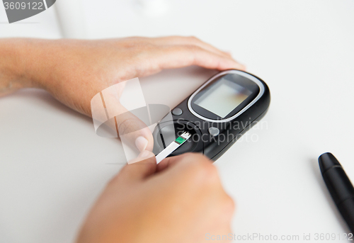 Image of close up of woman making blood test by glucometer