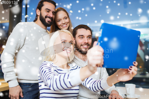 Image of happy friends with tablet pc taking selfie at cafe