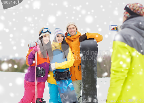 Image of happy friends with snowboards and smartphone