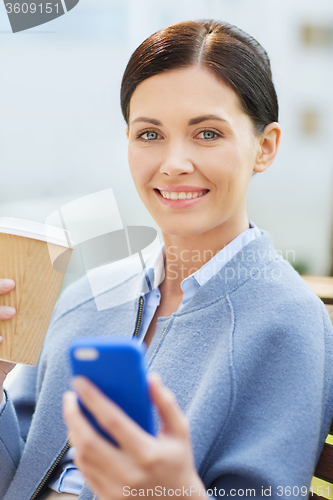 Image of smiling woman with coffee and smartphone