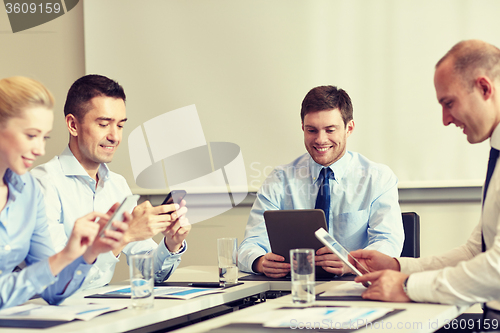 Image of smiling business people with gadgets in office