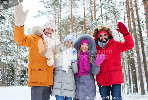 Image of group of friends waving hands in winter forest