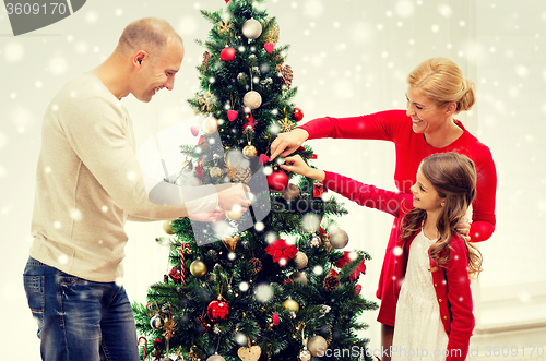Image of smiling family decorating christmas tree at home