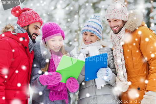 Image of smiling friends with tablet pc in winter forest