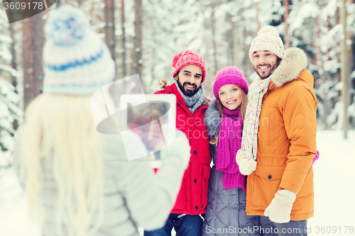 Image of smiling friends with tablet pc in winter forest