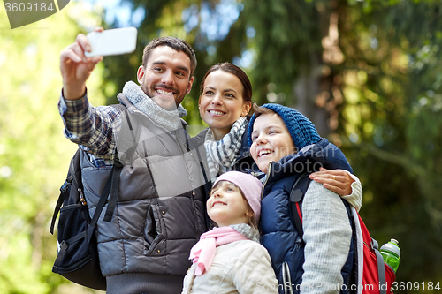 Image of family taking selfie with smartphone in woods