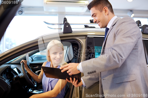 Image of happy woman with car dealer in auto show or salon