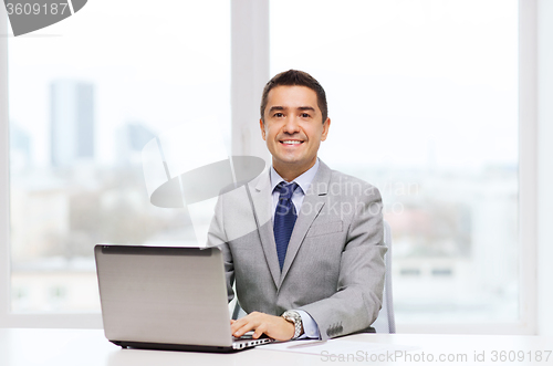 Image of smiling businessman with laptop and papers