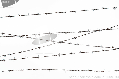 Image of barb wire fence over gray sky