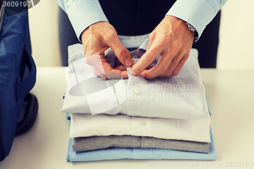 Image of businessman packing clothes into travel bag