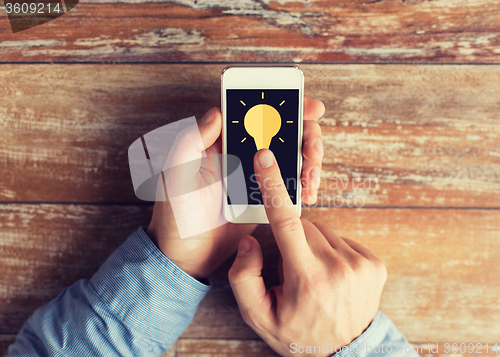 Image of close up of male hands with smartphone on table