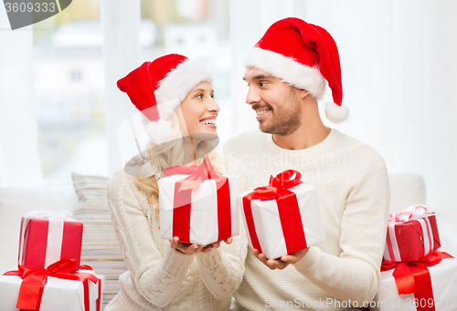 Image of happy couple at home exchanging christmas gifts