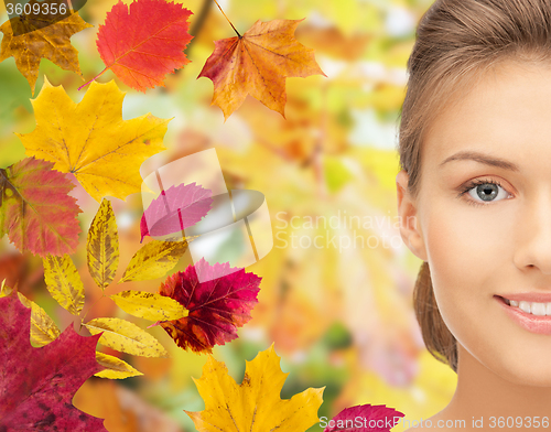 Image of beautiful young woman face over autumn leaves