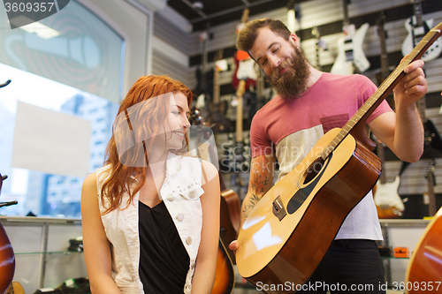 Image of couple of musicians with guitar at music store