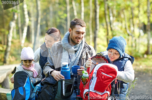 Image of happy family with backpacks and thermos at camp