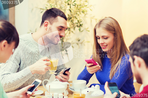 Image of group of friends with smartphones meeting at cafe