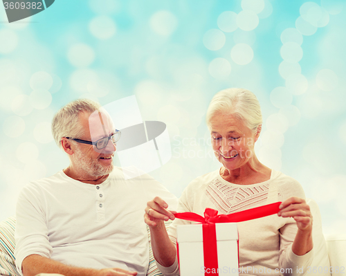 Image of happy senior couple with gift box at home