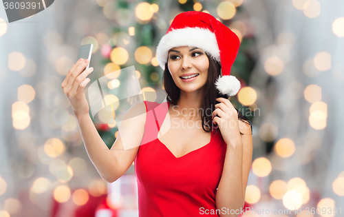 Image of woman in santa hat taking selfie by smartphone