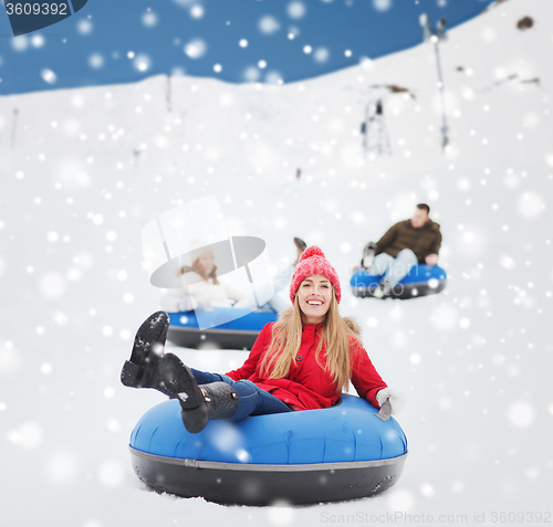 Image of group of happy friends sliding down on snow tubes