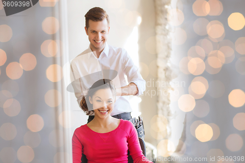 Image of happy woman with stylist making hairdo at salon