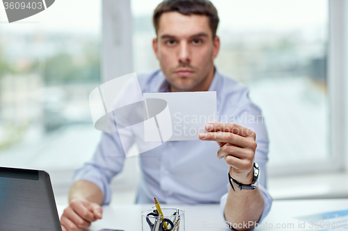 Image of businessman showing blank paper card at office