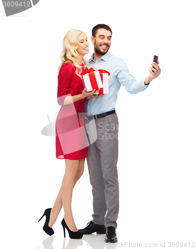 Image of happy couple with smartphone and gift boxes