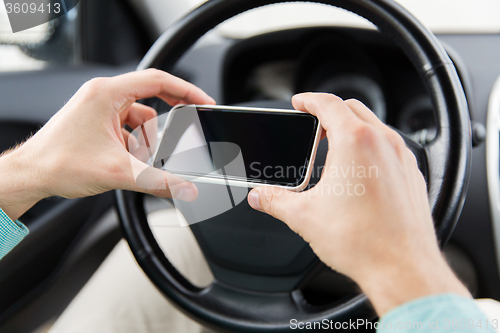 Image of close up of man hand with smartphone driving car