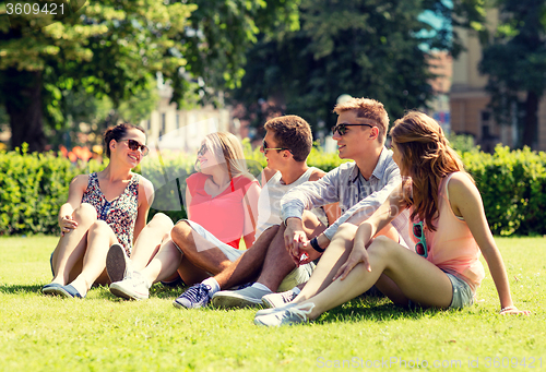 Image of group of smiling friends outdoors sitting on grass