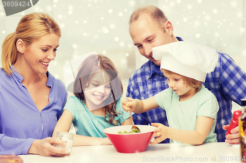 Image of happy family with two kids making salad at home