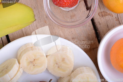 Image of healthy strawberry and bananas slices on wooden background