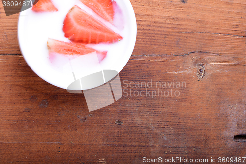 Image of Slice of pie with strawberry on white plate, milk drink, wooden background. Top view