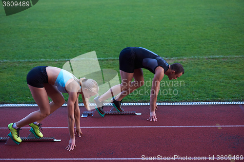 Image of woman group  running on athletics race track from start