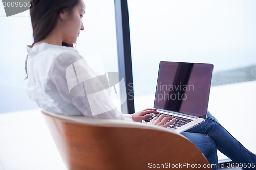 Image of relaxed young woman at home working on laptop computer