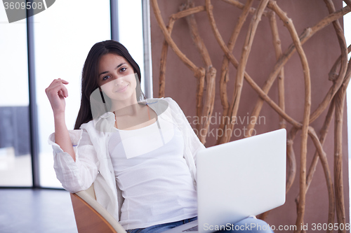 Image of relaxed young woman at home working on laptop computer