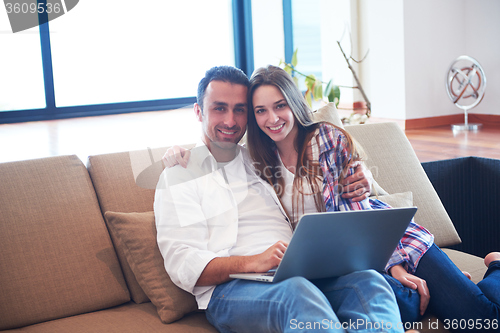 Image of relaxed young couple working on laptop computer at home